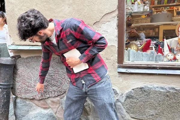 En lokal Guide visar den gömda runstenen i Gamla stan – en relik från vikingatiden instoppad i en medeltida mur.