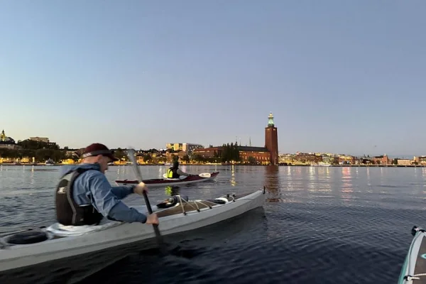 Paddling mot en illumnerad skyline i Stockholm med Stadshuset i bakgrunden